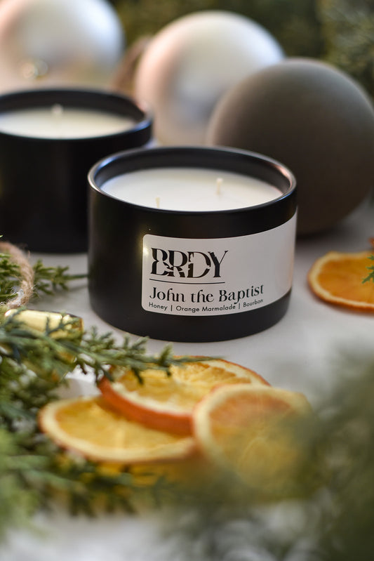 Christmas candle in a black tin with a label on a surface with decorative elements