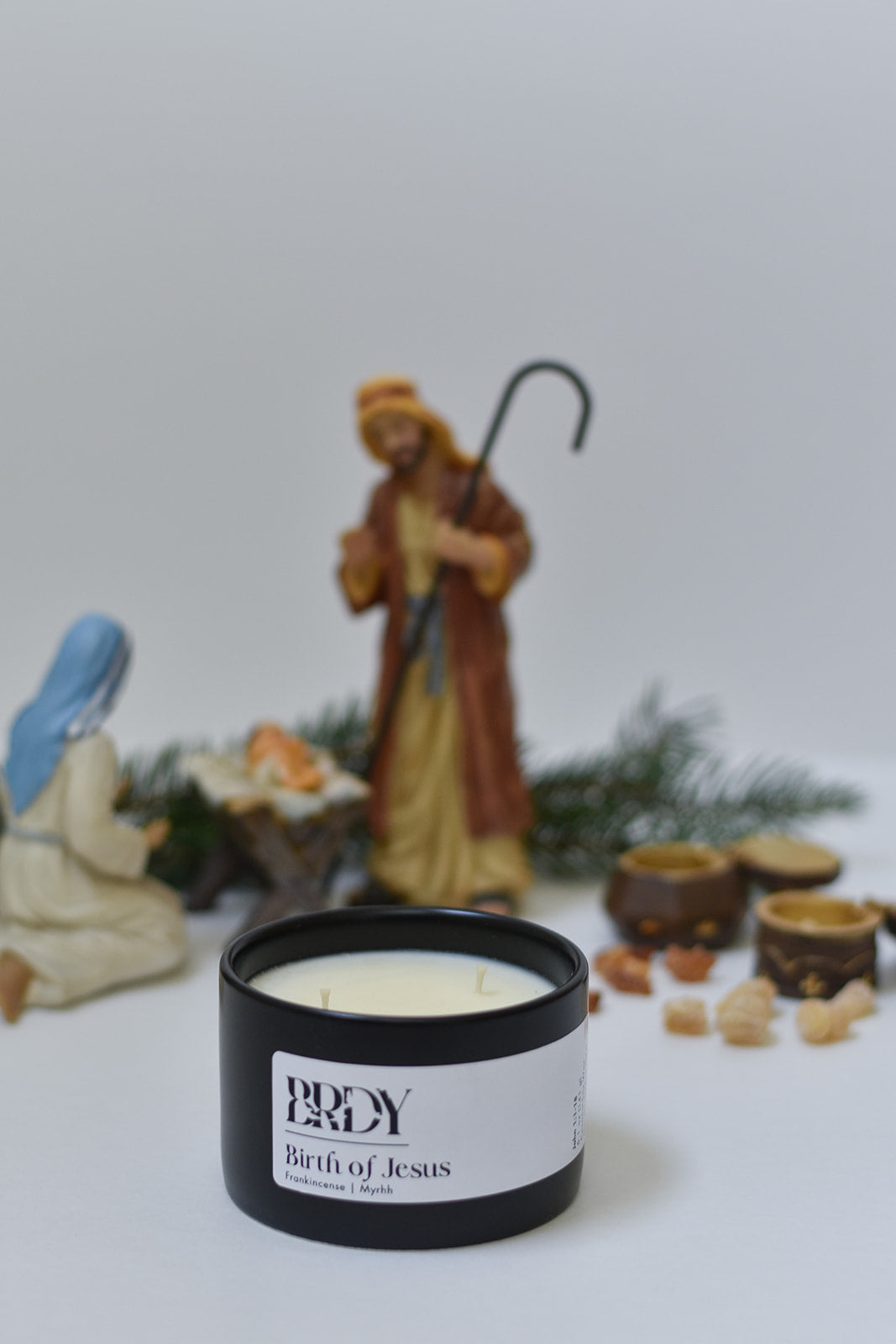 Candle labeled 'Birth of Jesus' with nativity scene figurines in the background